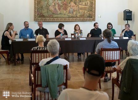 fotografia. spotkanie literacki środek europy w ramach festiwalu art piknik w willi decjusza. goście siedzą przy długim stole w sali marceliny czartoryskiej. na pierwszym planie publiczność siedząca na krzesłach.